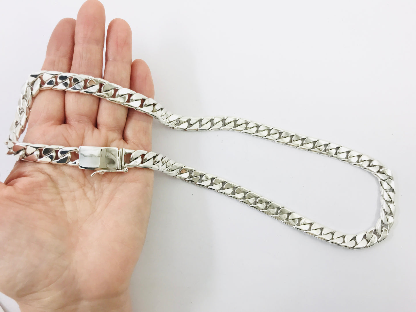 Silver chain held by a hand on a white background